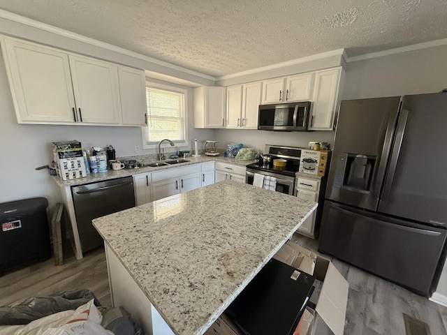 kitchen featuring light stone counters, wood finished floors, a sink, stainless steel appliances, and white cabinetry