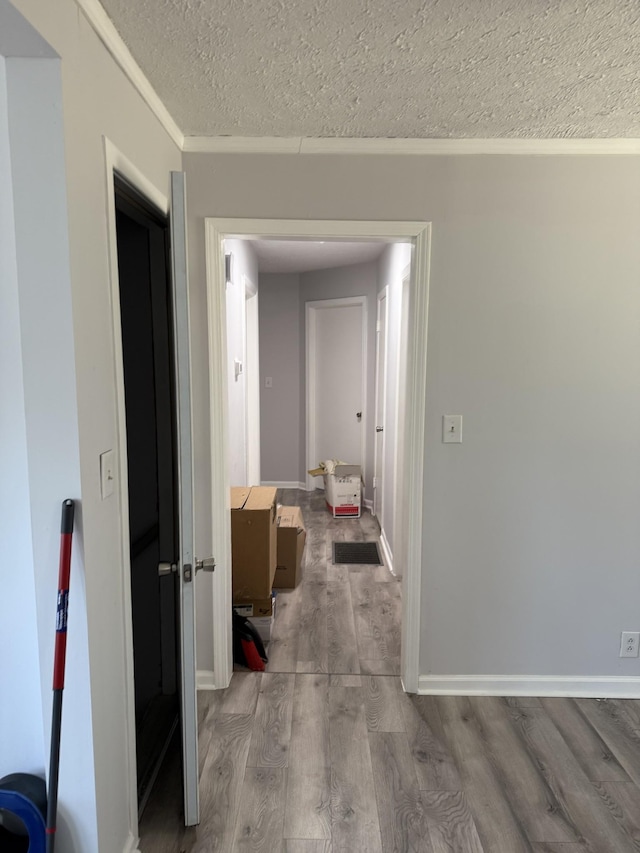 corridor featuring a textured ceiling, baseboards, and wood finished floors