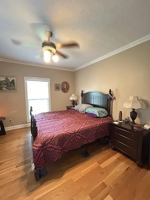 bedroom with ornamental molding, a textured ceiling, baseboards, and wood finished floors