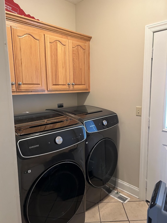 washroom featuring light tile patterned floors, visible vents, baseboards, washing machine and clothes dryer, and cabinet space