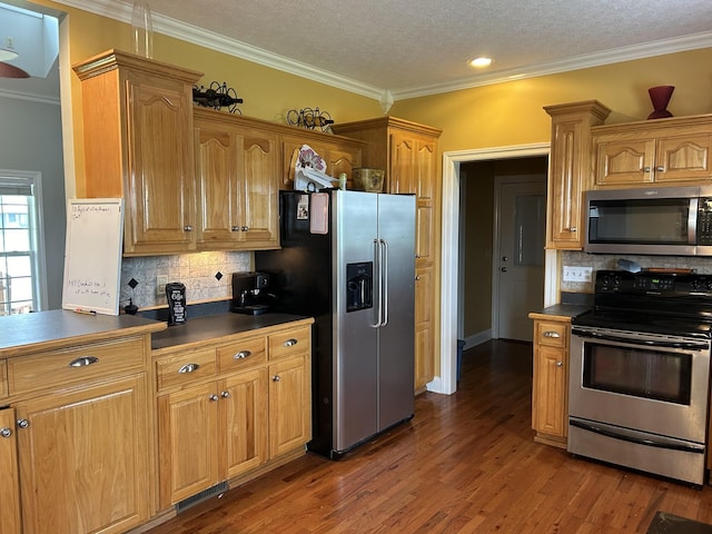 kitchen with dark wood finished floors, dark countertops, crown molding, and appliances with stainless steel finishes