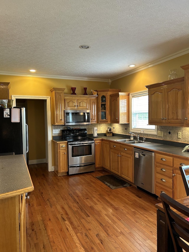 kitchen featuring a sink, decorative backsplash, appliances with stainless steel finishes, and hardwood / wood-style floors