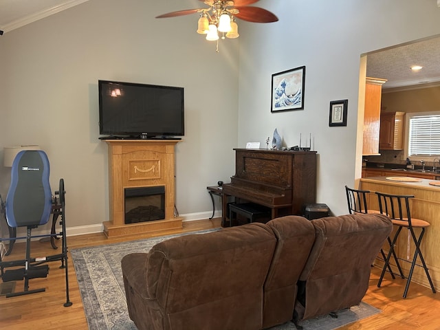 living room with a fireplace with raised hearth, crown molding, and light wood finished floors