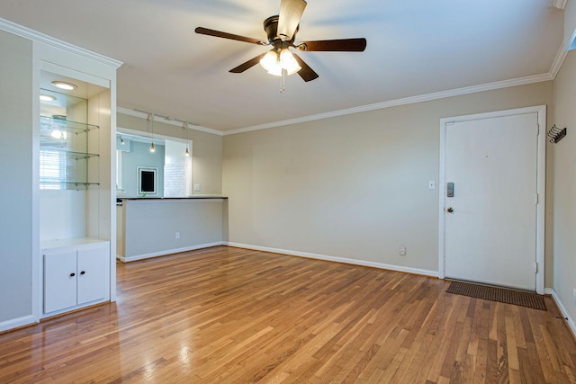 spare room featuring light wood-type flooring, baseboards, ceiling fan, and crown molding