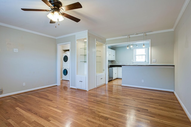 unfurnished living room with light wood-style flooring, baseboards, stacked washer / drying machine, and ornamental molding