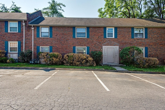 multi unit property with brick siding and uncovered parking