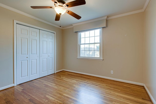 unfurnished bedroom featuring ceiling fan, baseboards, ornamental molding, light wood-style floors, and a closet