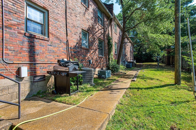 view of side of property with cooling unit, a lawn, and brick siding