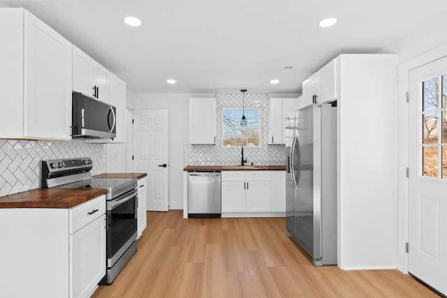 kitchen featuring white cabinets, light wood-style floors, appliances with stainless steel finishes, and wood counters