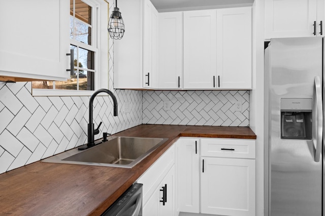 kitchen featuring decorative backsplash, wood counters, stainless steel refrigerator with ice dispenser, and a sink