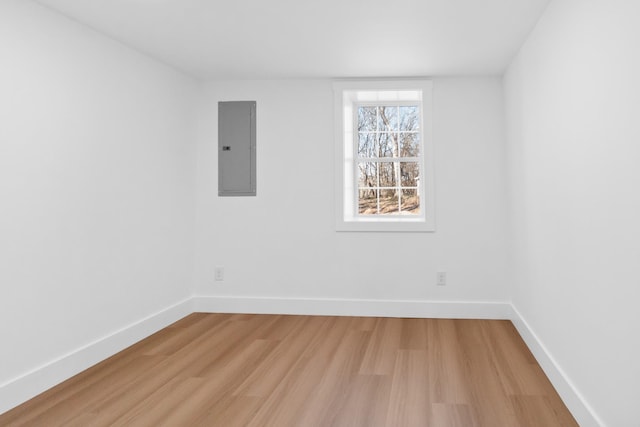 empty room featuring electric panel, light wood-style flooring, and baseboards