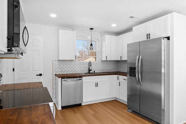 kitchen with visible vents, backsplash, butcher block counters, appliances with stainless steel finishes, and a sink