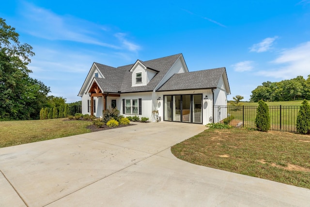 modern inspired farmhouse with driveway, a shingled roof, fence, a front yard, and an attached garage