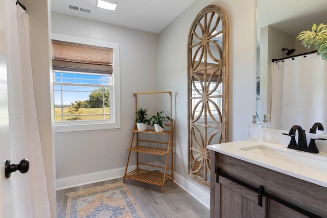 full bathroom with visible vents, vanity, baseboards, and wood finished floors