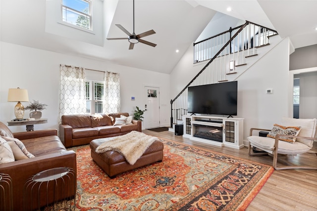 living area featuring stairs, plenty of natural light, wood finished floors, and high vaulted ceiling