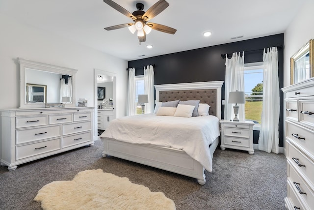 bedroom with visible vents, multiple windows, ensuite bath, and dark colored carpet