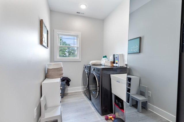 laundry area featuring visible vents, light wood finished floors, baseboards, laundry area, and washing machine and clothes dryer