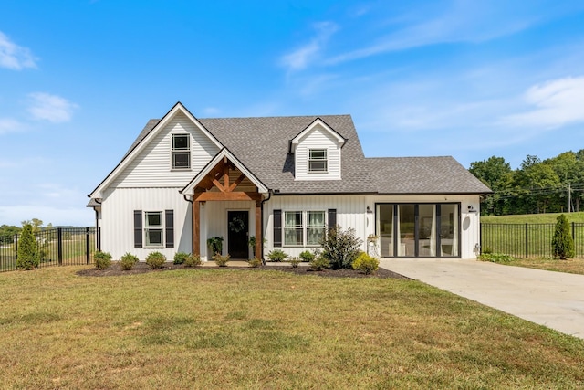 modern farmhouse style home featuring a front yard, concrete driveway, fence, and roof with shingles