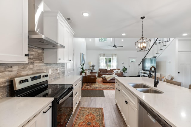 kitchen featuring a sink, wall chimney range hood, tasteful backsplash, appliances with stainless steel finishes, and light countertops