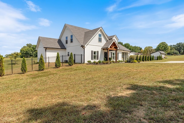 modern inspired farmhouse with a shingled roof, a front lawn, and fence