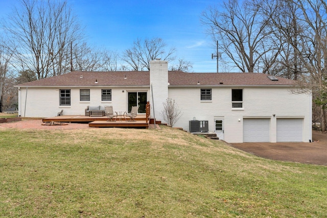 rear view of property featuring brick siding, a chimney, a garage, a yard, and driveway