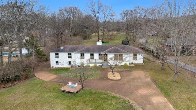 view of front facade featuring a front lawn, a chimney, and driveway