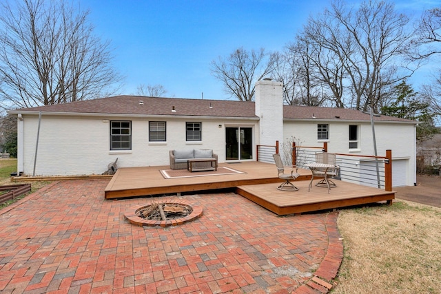 rear view of property featuring a fire pit, brick siding, a deck, and a chimney