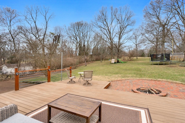 deck with a yard, a fire pit, a playground, and a trampoline