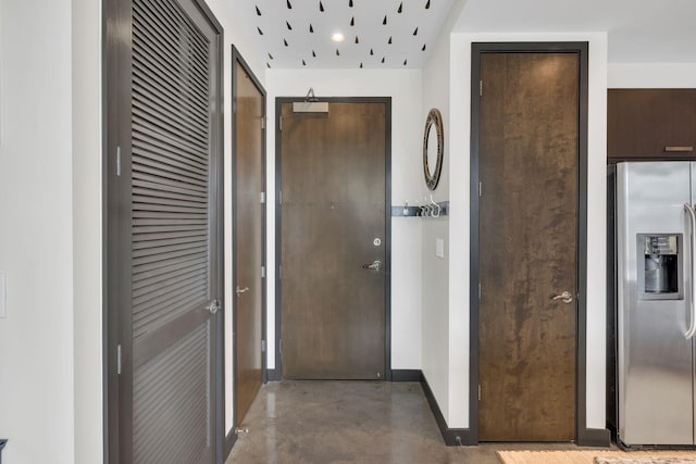 hall featuring baseboards and concrete flooring