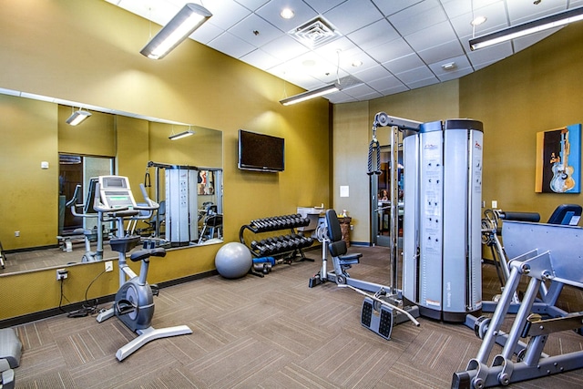 gym featuring a paneled ceiling, visible vents, carpet floors, and a towering ceiling