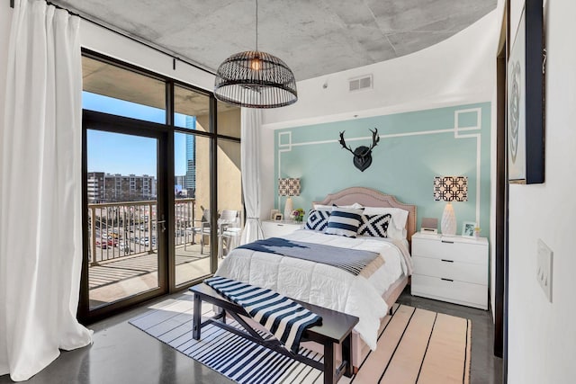 bedroom with a view of city, access to outside, finished concrete flooring, and visible vents