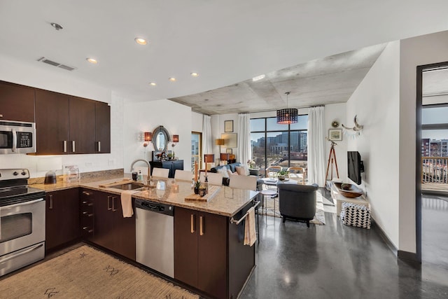 kitchen with visible vents, a sink, stainless steel appliances, dark brown cabinetry, and a peninsula