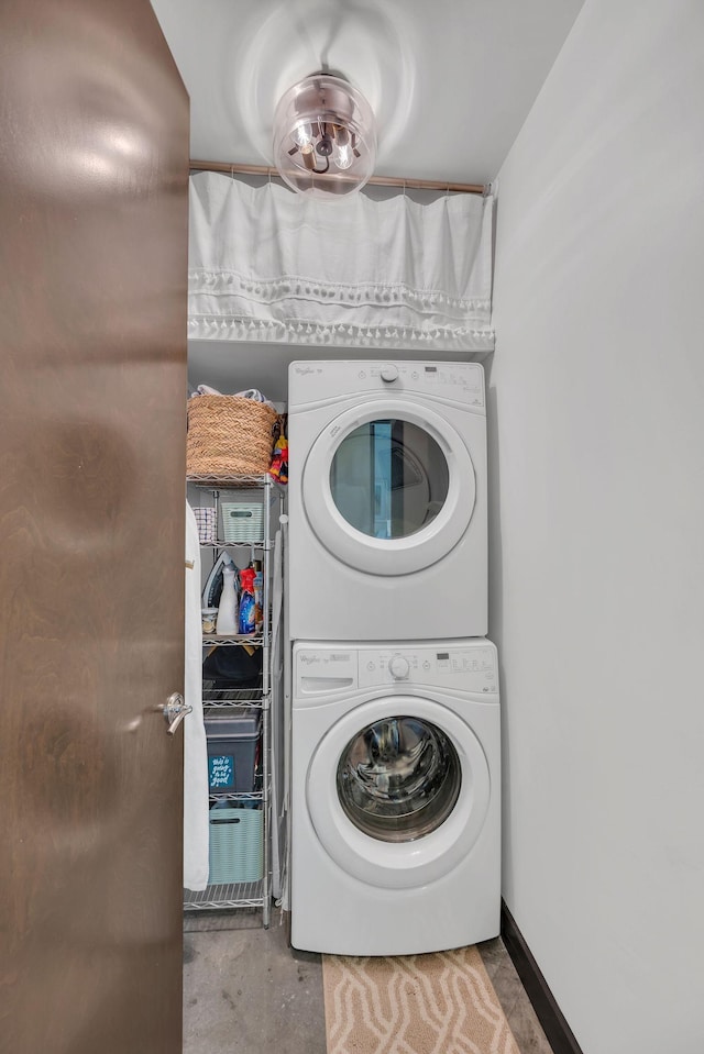 laundry area featuring stacked washer / drying machine, baseboards, and laundry area