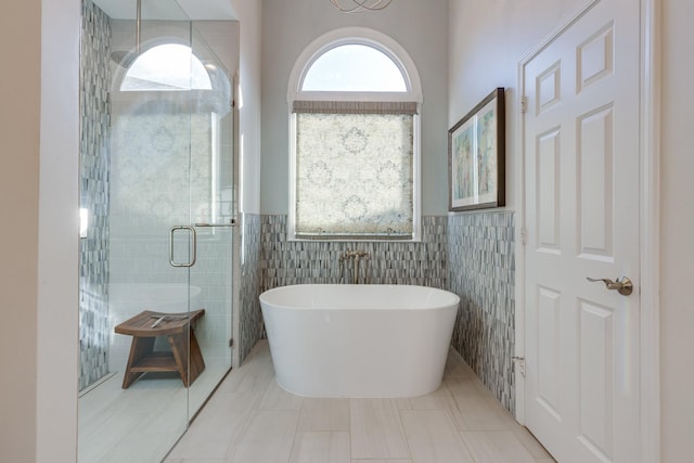 full bath with tile patterned floors, a freestanding tub, tile walls, and a stall shower