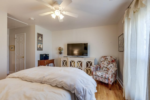 bedroom with a ceiling fan, attic access, and wood finished floors