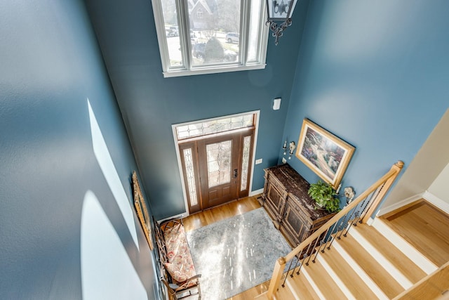 foyer with baseboards, stairs, a high ceiling, and wood finished floors