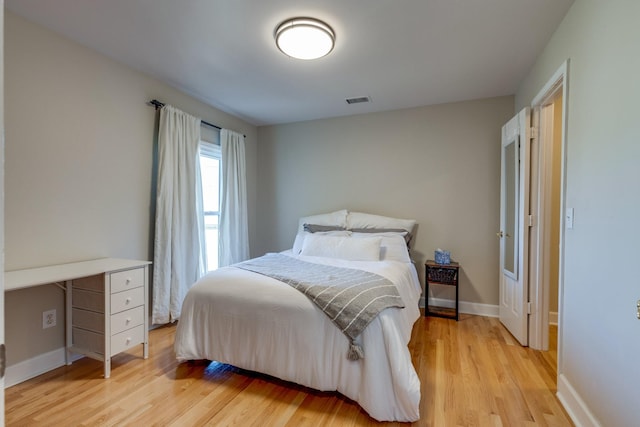 bedroom with visible vents, light wood-type flooring, and baseboards