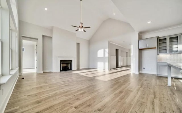 unfurnished living room with high vaulted ceiling, a ceiling fan, recessed lighting, a fireplace, and light wood finished floors