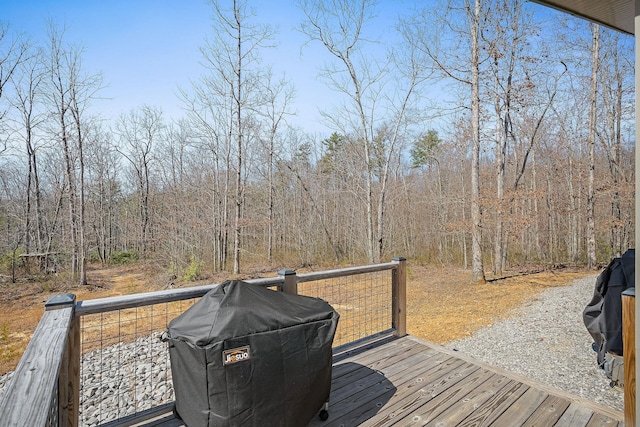 wooden terrace featuring grilling area and a forest view