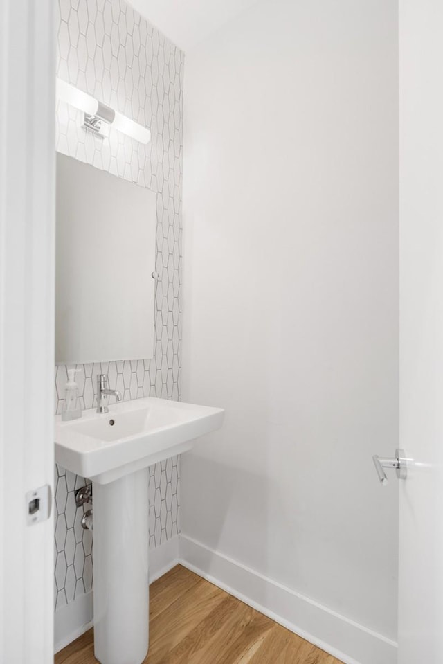 bathroom featuring decorative backsplash, baseboards, and wood finished floors