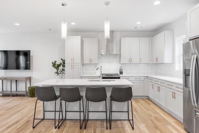 kitchen with appliances with stainless steel finishes, light wood-type flooring, a kitchen breakfast bar, and a sink