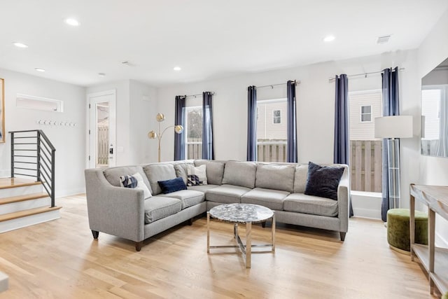 living room with recessed lighting, light wood-style flooring, and stairs