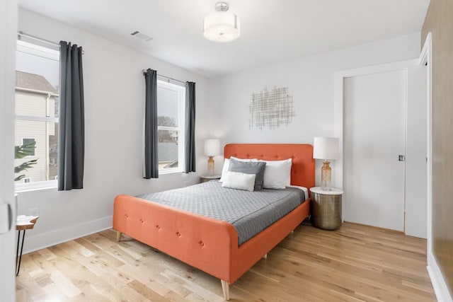 bedroom featuring light wood-type flooring, visible vents, and baseboards