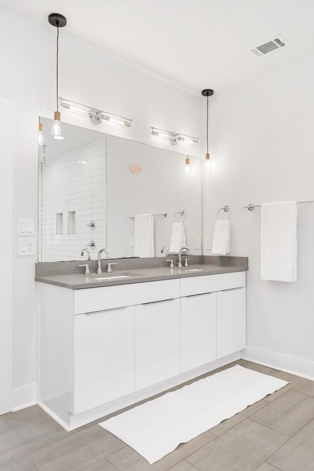 full bathroom with a sink, visible vents, baseboards, and double vanity