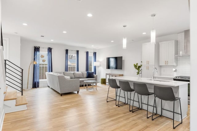 kitchen featuring stainless steel electric range oven, light wood-style flooring, a breakfast bar area, and a sink