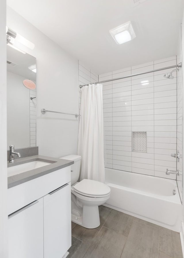 bathroom with vanity, visible vents, wood finish floors, shower / tub combo, and toilet