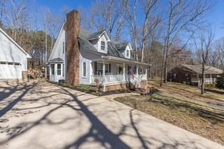 cape cod house with covered porch, a chimney, and a garage