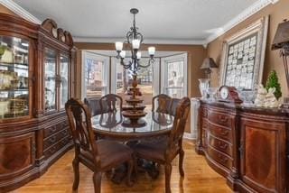 dining room featuring an inviting chandelier, light wood-type flooring, and ornamental molding