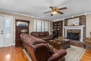 living room with ceiling fan, wood finished floors, a fireplace, and crown molding