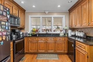 kitchen featuring brown cabinets, range with electric cooktop, a sink, dark countertops, and freestanding refrigerator